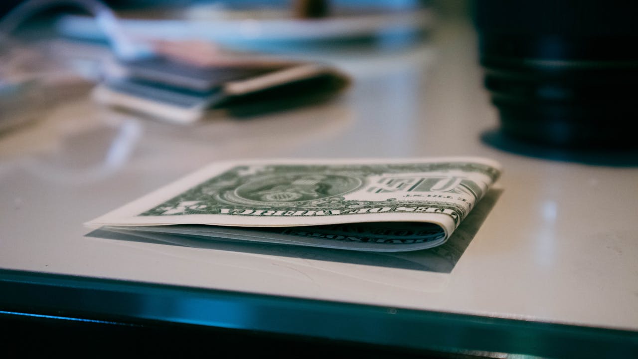 Detailed shot of a folded US dollar note on a reflective surface indoors.